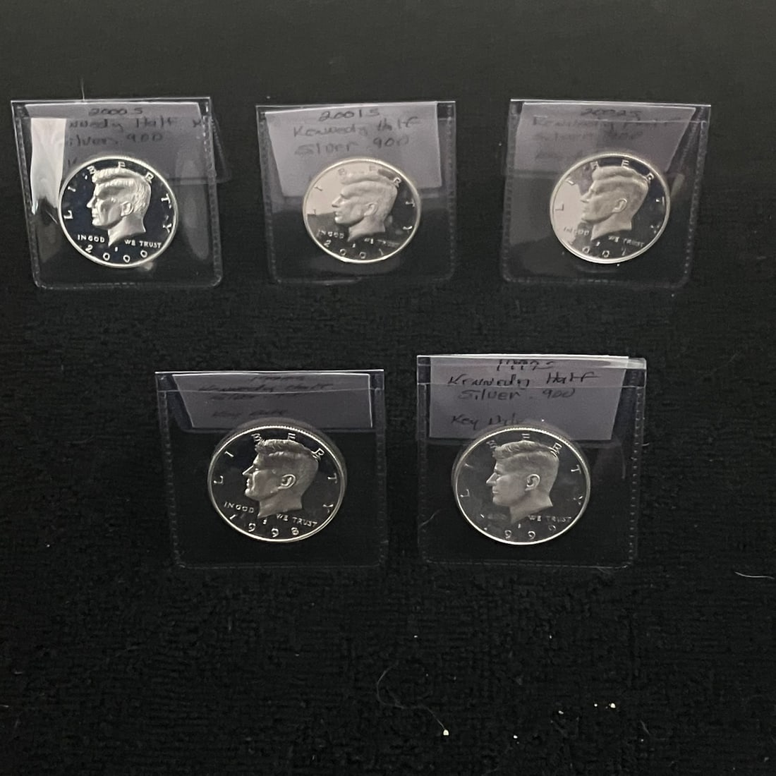 5 - Kennedy .90 Silver Half Dollar Cameo Proof: Lot of five Kennedy half dollar proof coins in individual plastic flips. Visible dates are 1998-S, 1999-S, 2000-S, 2001-S, and 2002-S. The coins show reflective fields and frosted devices consistent