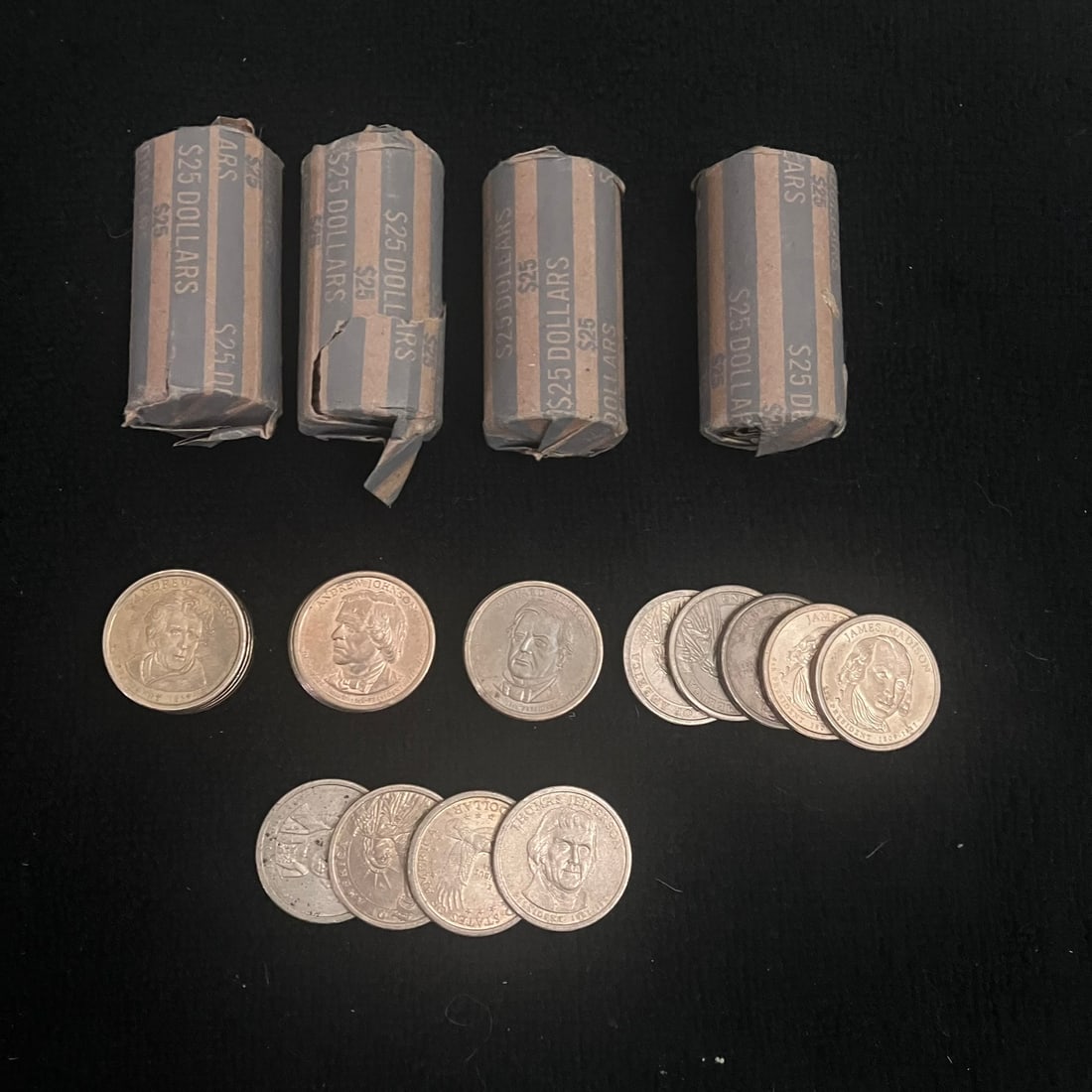 124 - U.S. $1 Dollar Coins: 124 U.S. dollar coins consisting of 4 paper-wrapped rolls marked “$25 DOLLARS” and multiple loose coins. Visible designs include presidential portrait obverses, Statue of Liberty reverses,