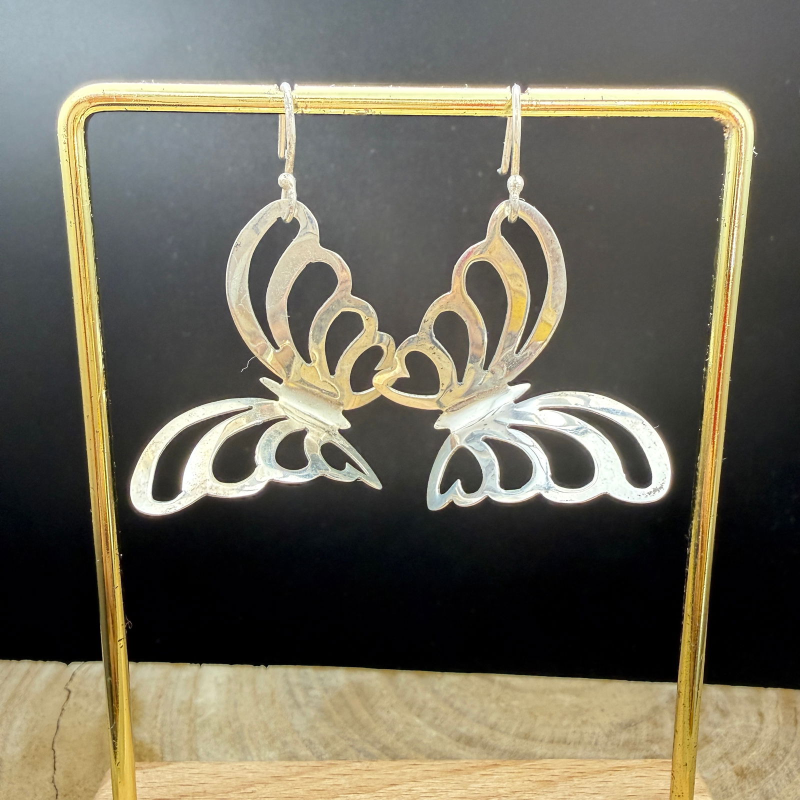 Sterling Silver Open Work Butterfly Dangle Earrings: This lot features a pair of sculptural sterling silver butterfly dangle earrings of unknown maker. Each earring is formed in an openwork butterfly motif with softly curved wings and a dimensional, lay