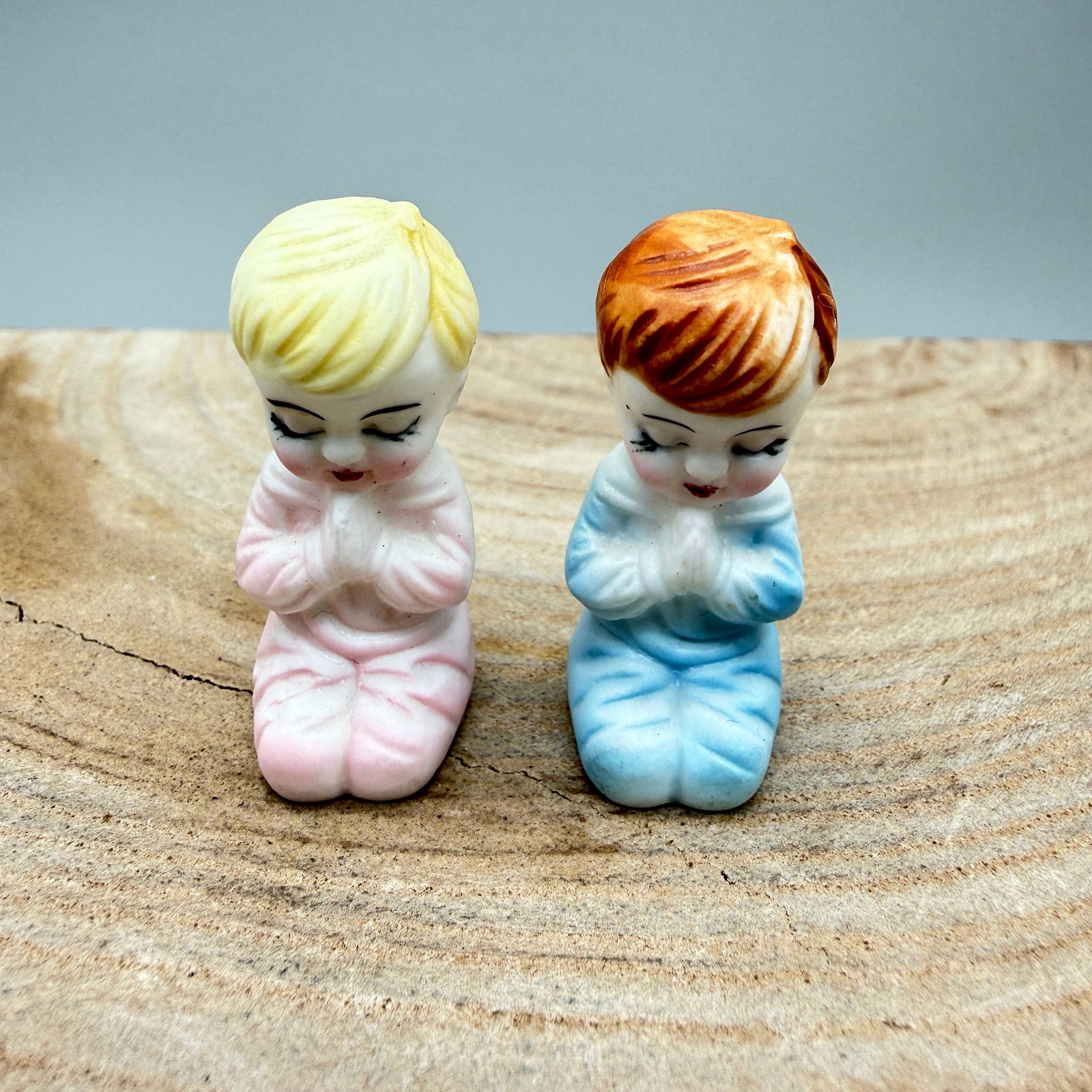 Pair Bone China Japan Praying Child Miniatures: Sweet vintage pair of bone china miniature figurines featuring kneeling praying children in pastel pink and blue. Each marked Bone China Japan (one retains original foil label). Charming mid-century d