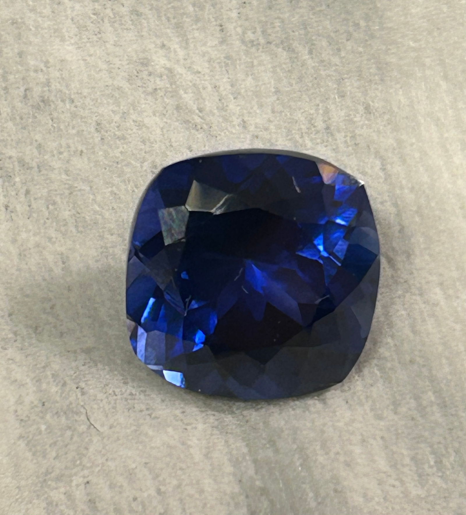 Deep Blue Sapphire Cushion Cut 12 ct from Sri Lanka: A large, valuable gemstone known for its intense, velvety, twilight-blue color, high clarity, and classic square/rounded cushion cut that maximizes brilliance, making it highly sought-after.