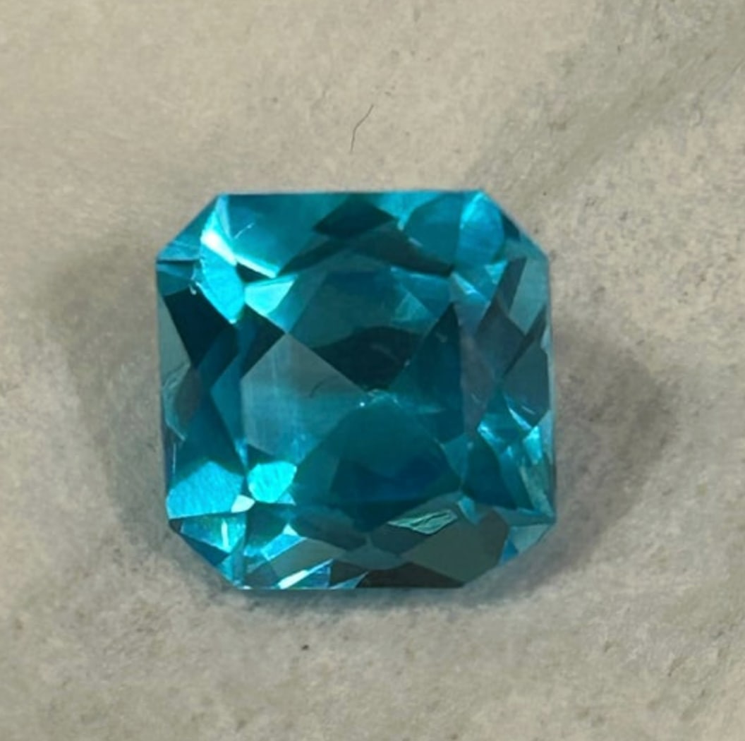 Neon Blue Paraiba Tourmaline Asscher Cut VVS 11.85ct from Brazil: high-value gemstone, characterized by its electric, tropical blue-green hue (the "neon" glow from copper), significant size (11.85 carats), Asscher cut for brilliance, VVS clarity (very, very slight