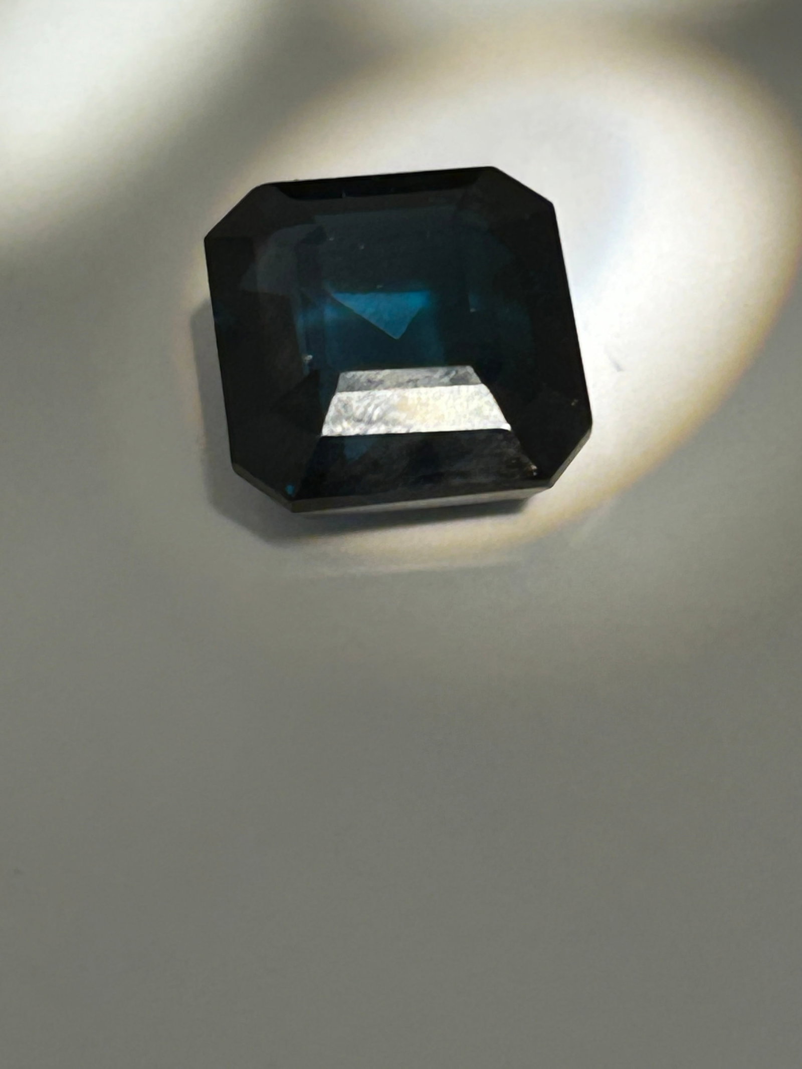 Large Mozambique Tourmaline 25ct Asscher Cut No Reserve Dark & Moody Gem: A large 25-carat tourmaline in an Asscher cut is a rare and luxurious gemstone, often characterized by its deep color saturation and architectural, geometric facet pattern. At this size, the stone act