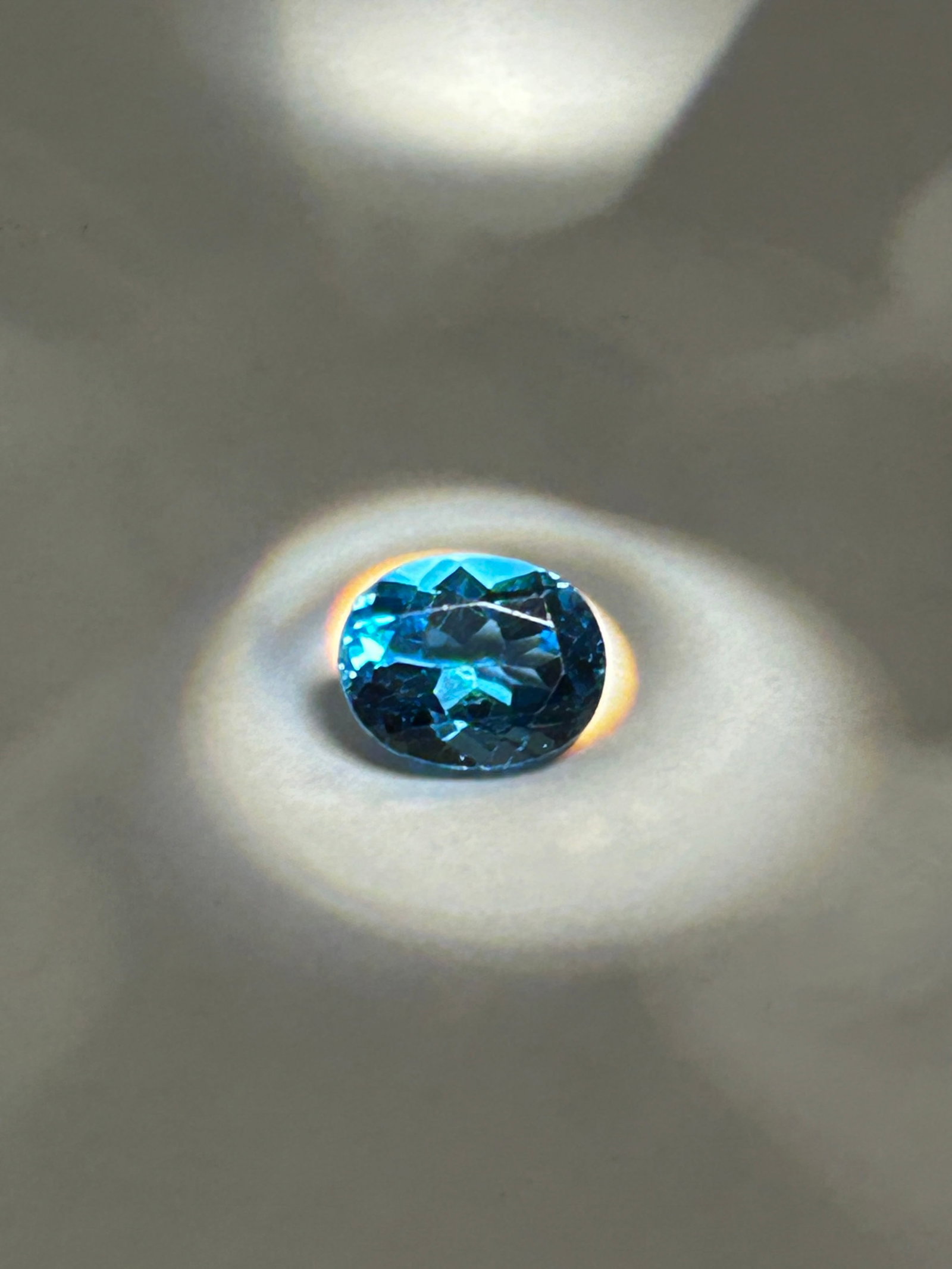 Natural Blue Topaz 1.33ct Oval Cut from Brazil IGI Certification No Reserve: a faceted, oval-cut gemstone originating from Brazil. Features the signature deep, dark intense grayish-blue color. Renowned for being "eye-clean" (IF-VVS), this durable gem offers high brilliant-cut