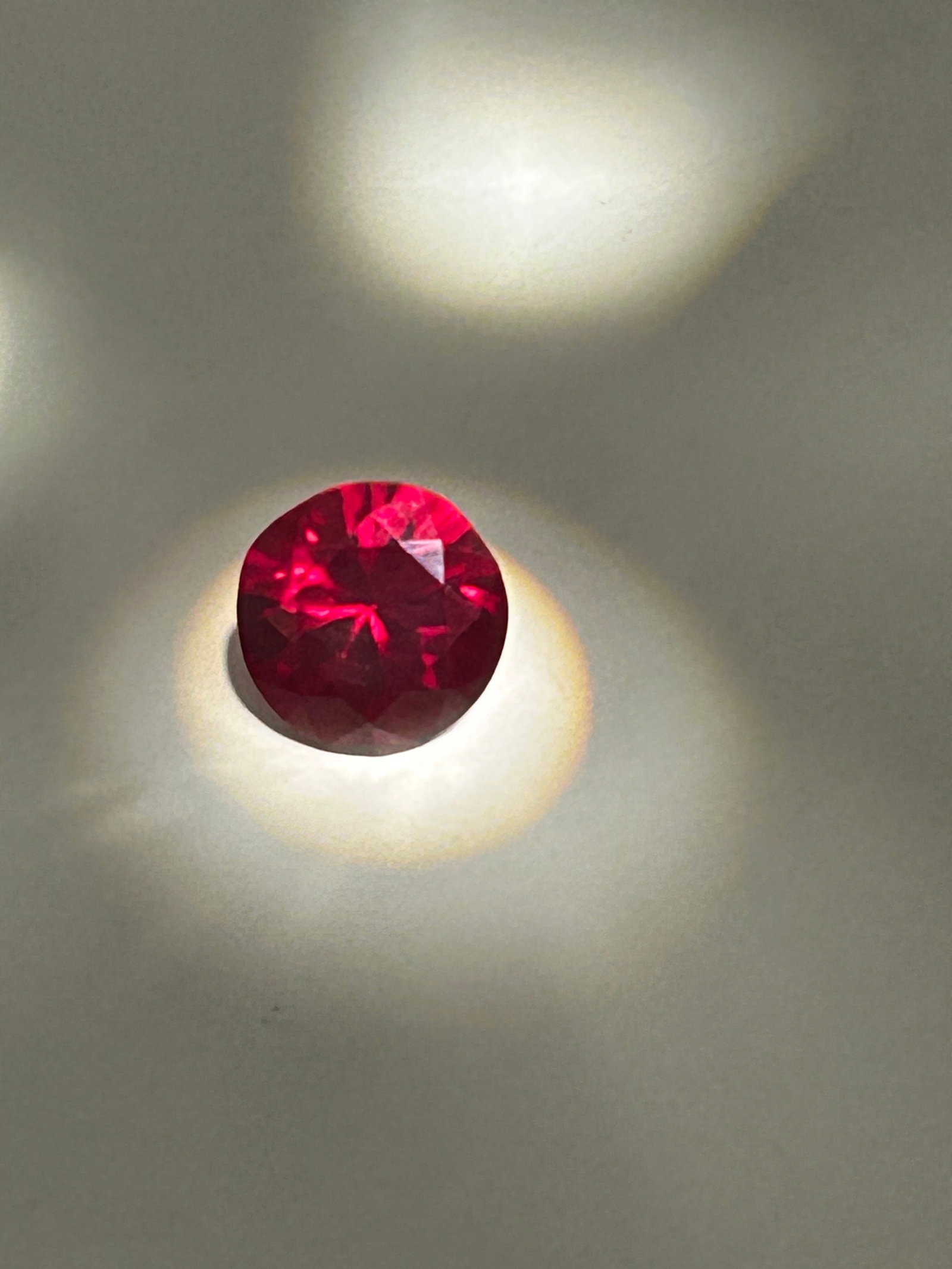 10ct Mozambique Deep Red Ruby Brilliant Round Cut No Reserve GGI Certified: sourced from Mozambique, is a large, high-value gemstone featuring a intense "blood red" or "pigeon blood" color. Cut as a brilliant round, it maximizes light reflection with symmetrical facets. These