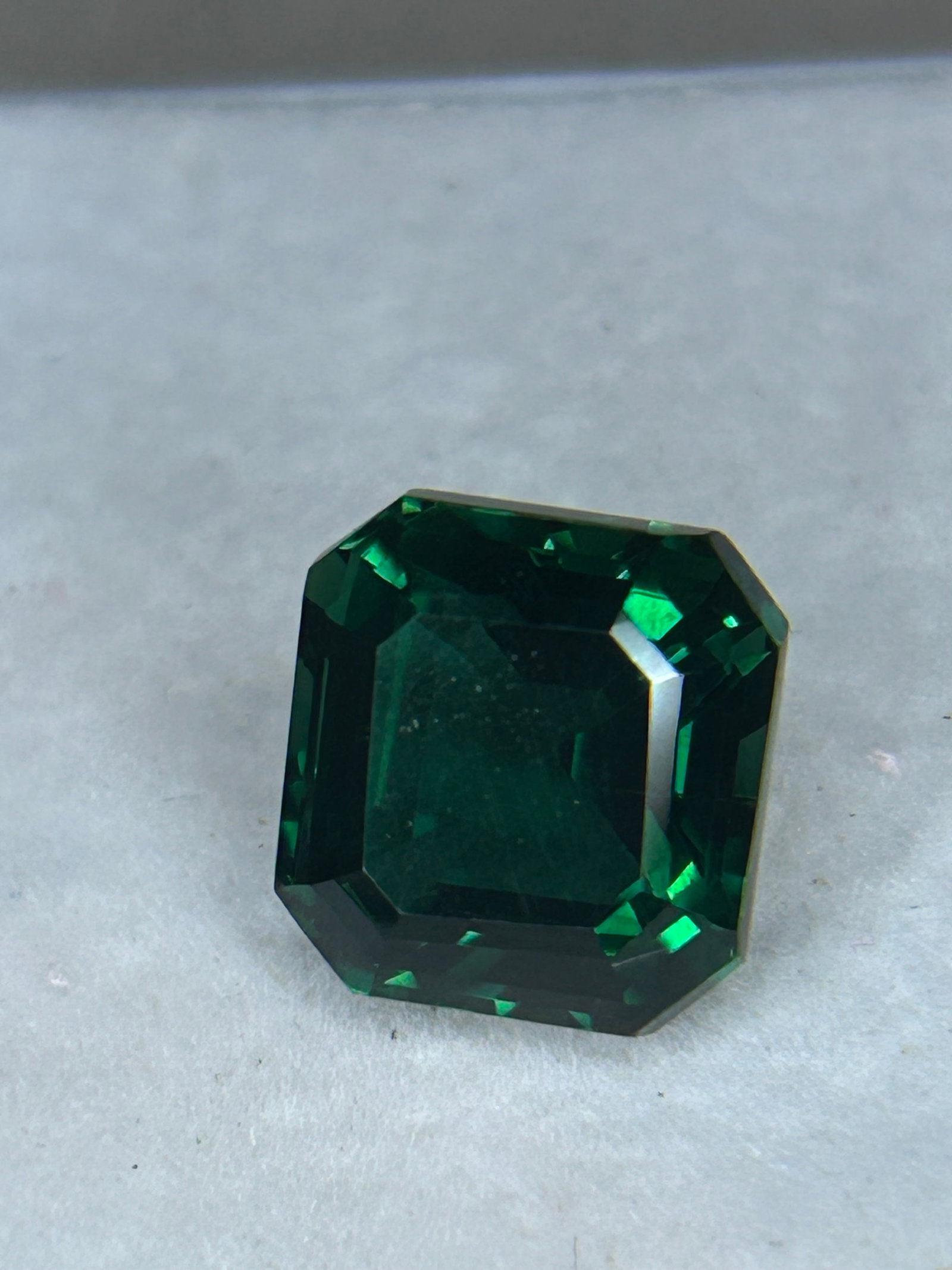7 Carat -- Natural Dark Green Emerald--- Asscher Cut --- EGL Certified: a rare, square step-cut gemstone featuring cropped corners, parallel facets, and an Art Deco "hall-of-mirrors" geometric pattern. At this substantial size, high-end natural emeralds often display deep