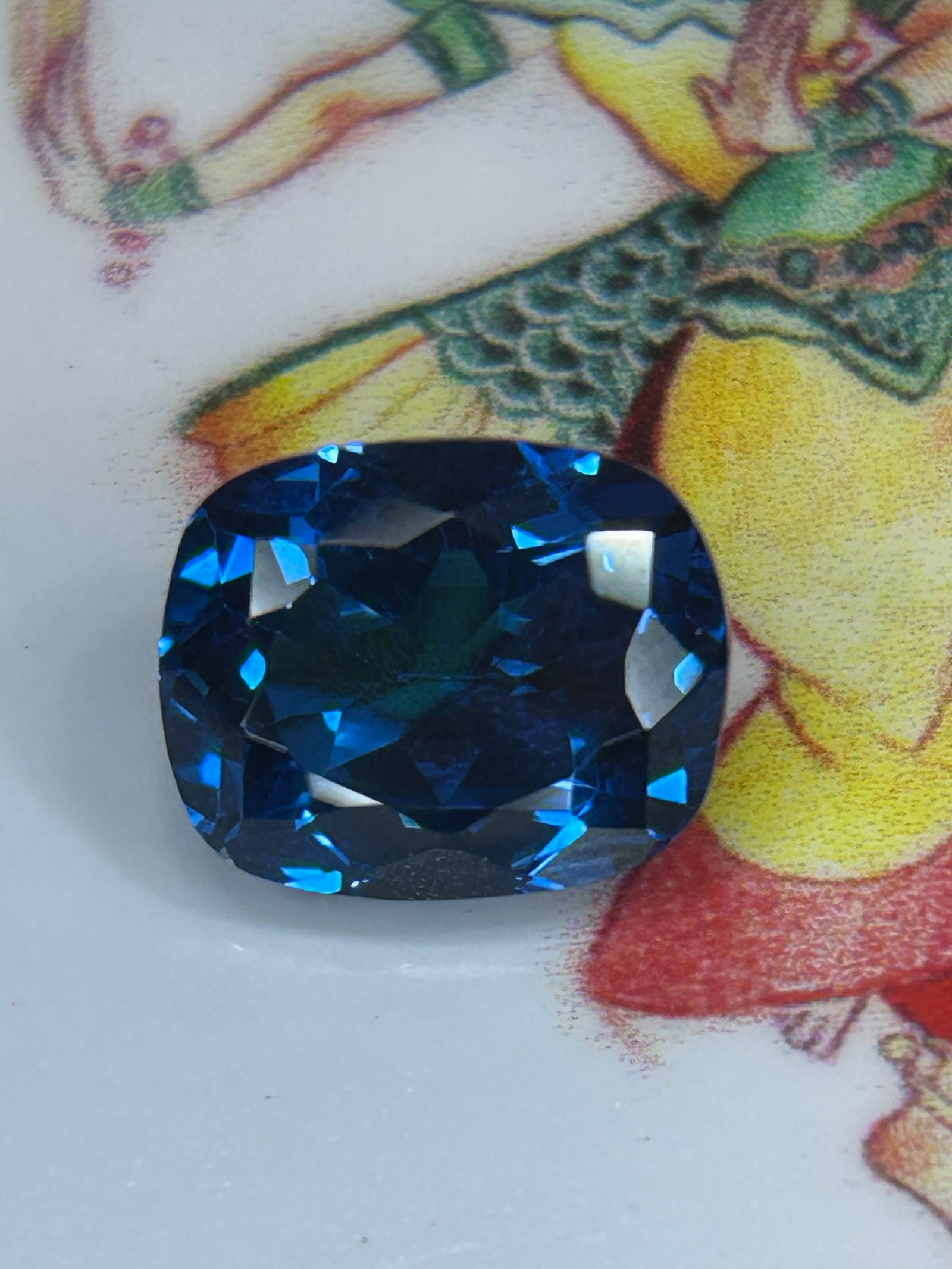 6.30 Carat Natural Brazilian Swiss Blue Topaz Mixed Cushion Cut: Earth-mined blue topaz from Brazil featuring a vibrant electric cyan-blue color, rounded-corner pillow shape, and a mixed brilliant-step facet arrangement.