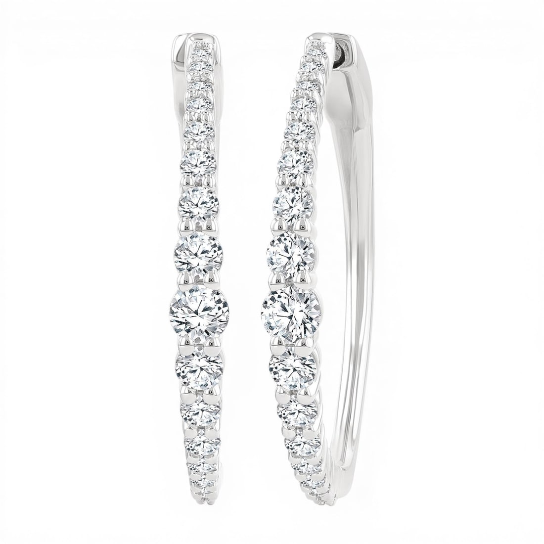 1.0ctw Graduated Diamond Riviera 14K White Gold Hoop Earrings: An exquisite masterpiece of haute joaillerie, this breathtaking Riviera pair of earrings featuring White Diamond is a true treasure. Showcasing the gems in a Riviera arrangement, the earrings consists