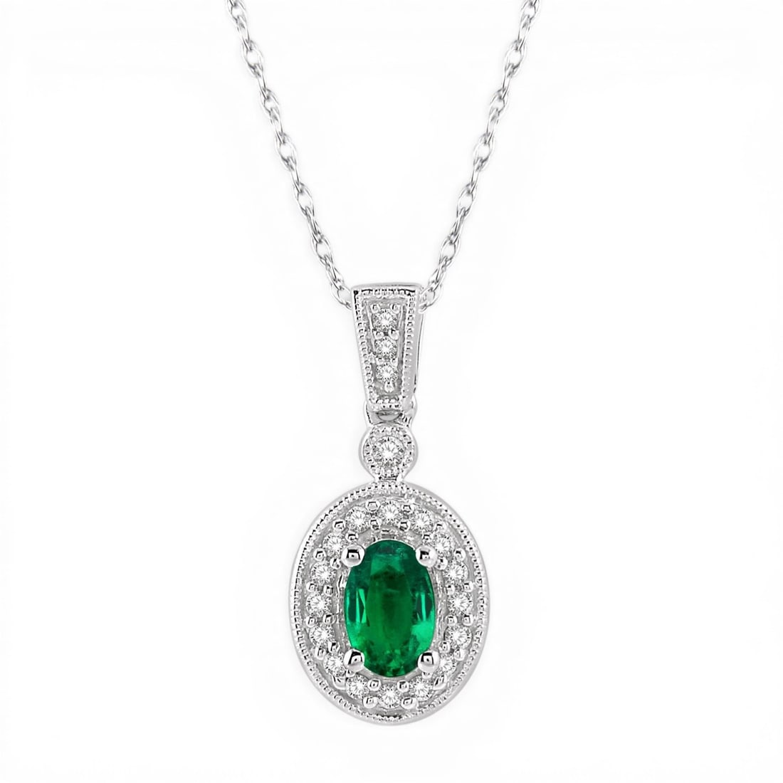 6x4mm Oval Emerald and 0.12ctw Diamond 14K White Gold Pendant: Exuding opulence and grace, this elegant Halo pendant featuring Emerald, White Diamond is crafted for the distinguished. Showcasing the gems in a Halo arrangement, the pendant consists of 2.1 grams of