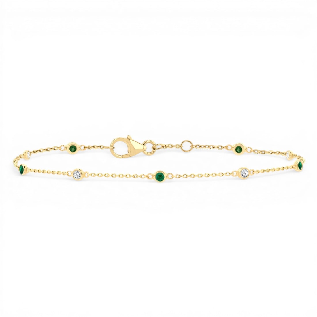 1.8mm Emerald and 0.11ctw Diamond 14K Yellow Gold Bracelet: Captured in a moment of brilliance, this stunning Bezel Set Station bracelet featuring Emerald, White Diamond speaks to the connoisseur. The gemstones are nestled within a Station framework, supported