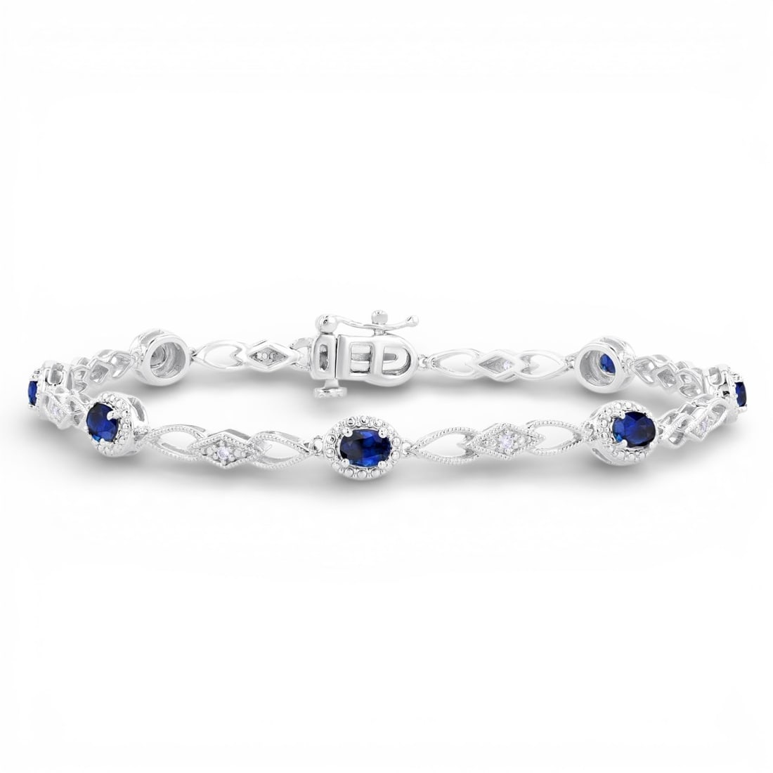 4x3mm Oval Blue Sapphire and 0.06 ctw Diamond 10K White Gold Bracelet: Rare and radiant, this exquisite Fancy Link bracelet featuring Blue Sapphire, White Diamond offers a touch of the extraordinary. Showcasing the gems in a Cluster arrangement, the bracelet consists of 