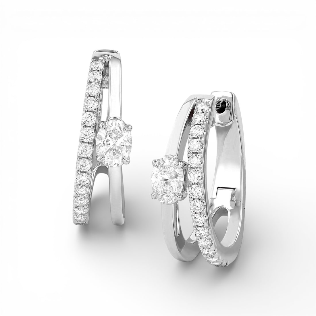 0.86 ctw Paradox Oval 2-Row Diamond 18K White Gold Earrings: Epitomizing grandeur, this breathtaking Paradox Oval 2-Row pair of earrings featuring White Diamond stands as a beacon of refined taste. Showcasing the gems in a Double-Band Suspension arrangement, th