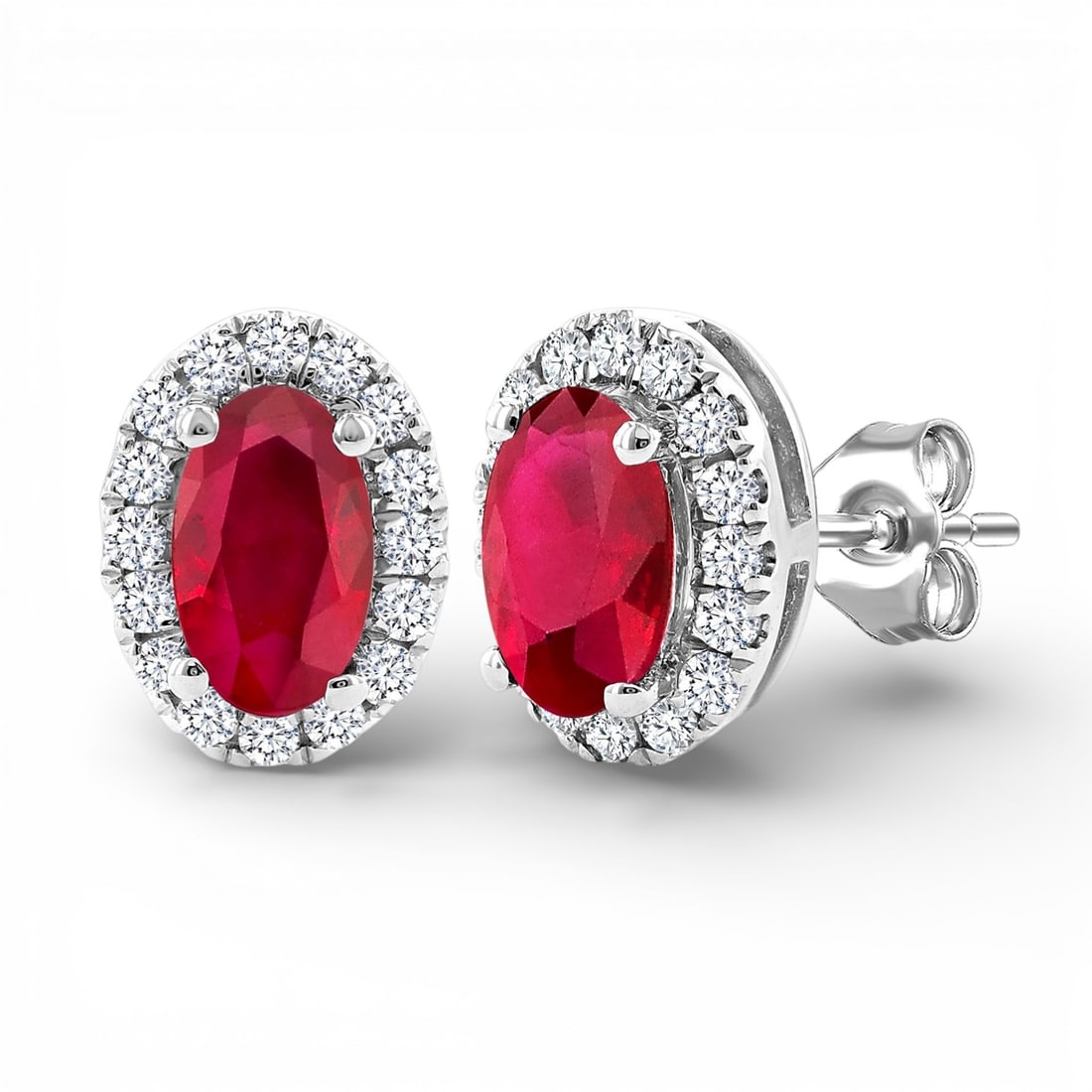 5x3mm Oval Ruby and 0.14 ctw Diamond 10K White Gold Earrings: A symphony of light and color, this stunning Halo pair of earrings featuring Ruby, White Diamond embodies the pinnacle of luxury. Securely held in a classic Halo design, the earrings are forged from 0