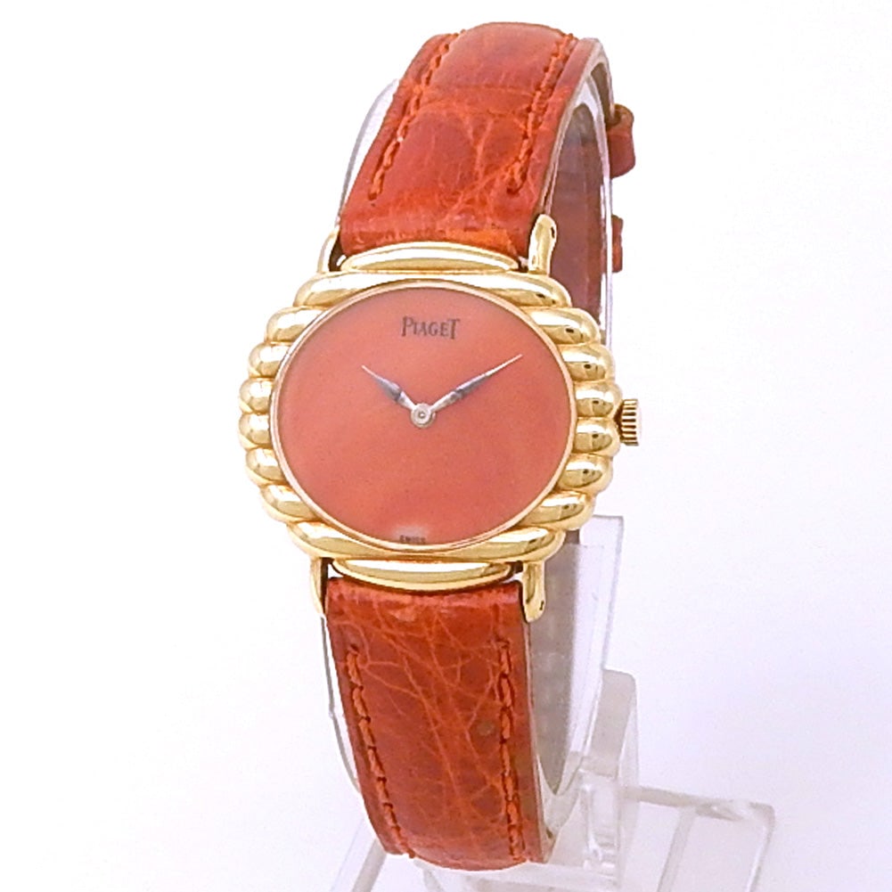 Piaget Vintage 98170 18K Yellow Gold Orange Dial: The Piaget Vintage, Reference 98170, is a captivating expression of refined femininity and Swiss luxury. Crafted in a warm 18k Yellow Gold case, this ladies' timepiece is distinguished by its vibrant 