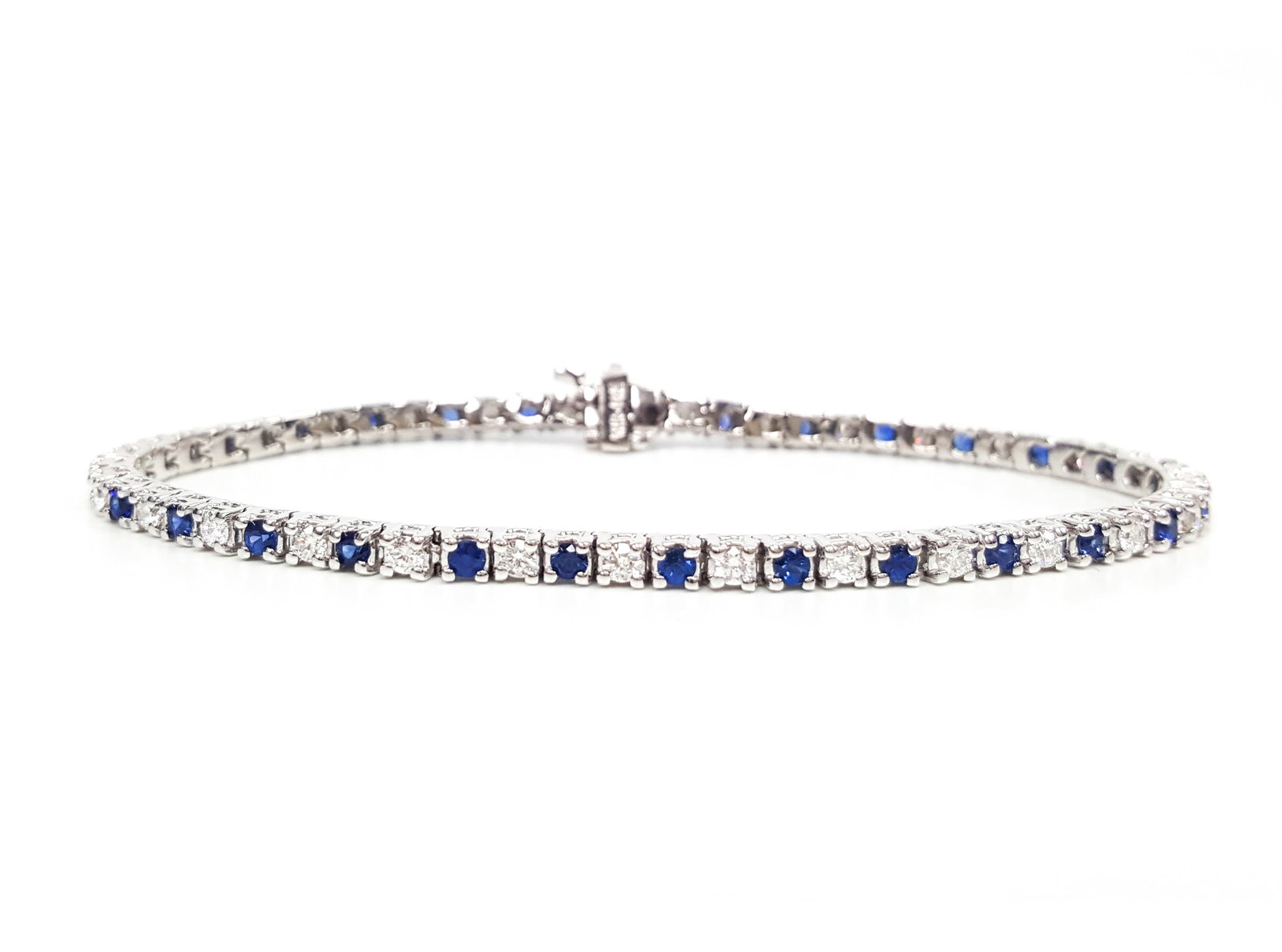 5.76ctw Blue Sapphire and Diamond 14K White Gold Bracelet: Rare and radiant, this breathtaking Alternating Line bracelet featuring White Diamond, Blue Sapphire offers a touch of the extraordinary. Showcasing the gems in a Four-Prong Line arrangement, the brac