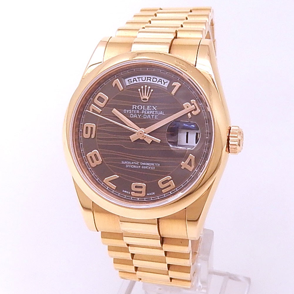 Rolex Day-Date 118205 18k Rose Gold Chocolate Wave Dial: The Rolex Day-Date, Reference 118205, is an exquisite expression of timeless luxury. Encased in 18k Rose Gold, this timepiece features a captivating Chocolate wave dial that radiates warm sophisti