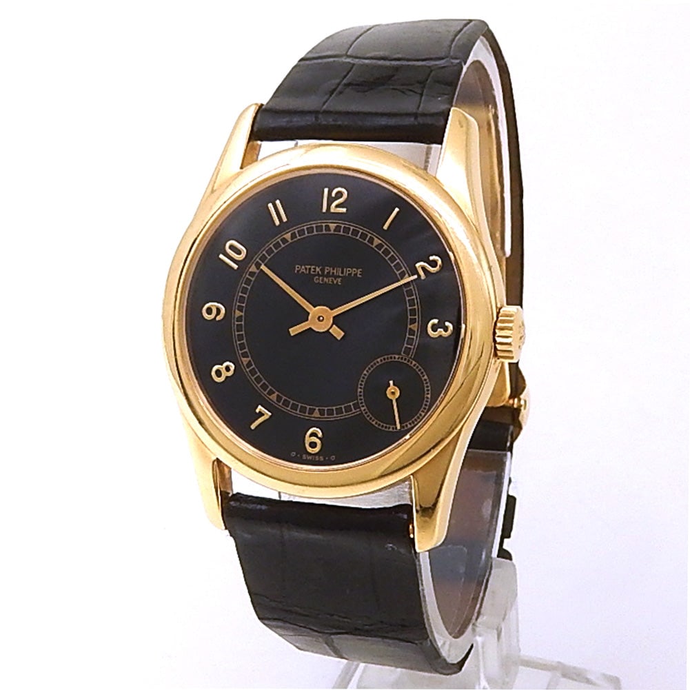 Patek Philippe Calatrava 5000J 18k Yellow Gold Black Dial: The Patek Philippe Calatrava, Reference 5000J, exemplifies the pinnacle of understated elegance and classic dress watch design. Encased in radiant 18k yellow gold, this timepiece features a deep black