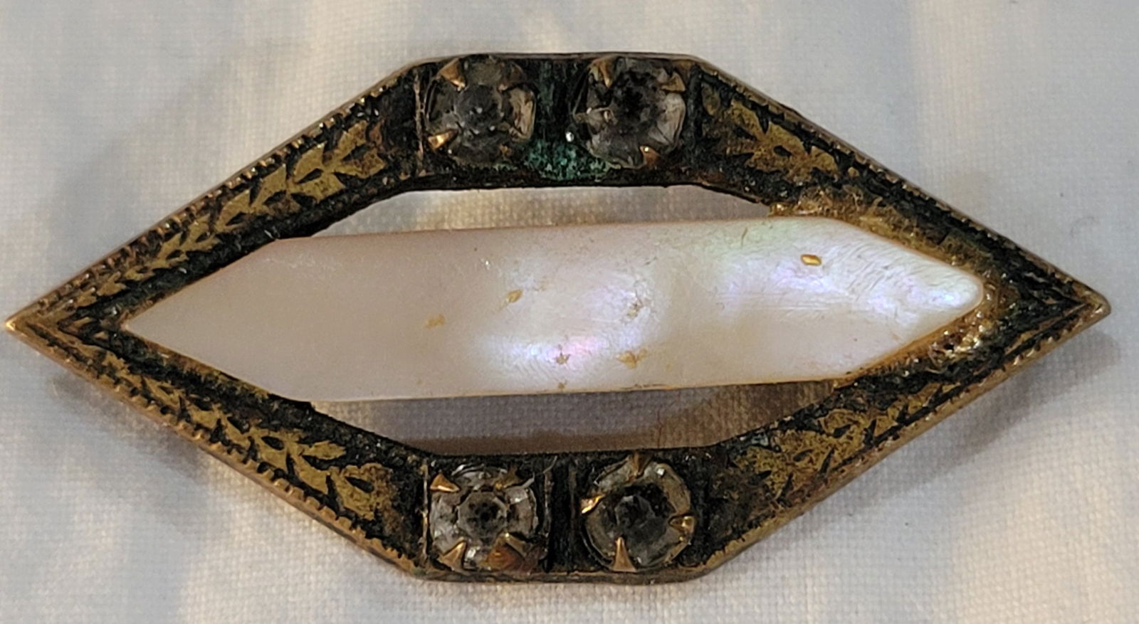 Vintage Art Deco era marquise-shaped brooch pin featuring mother of pearl: central mother of pearl inlay surrounded by decorative filigree and rhinestones in a sterling silver setting