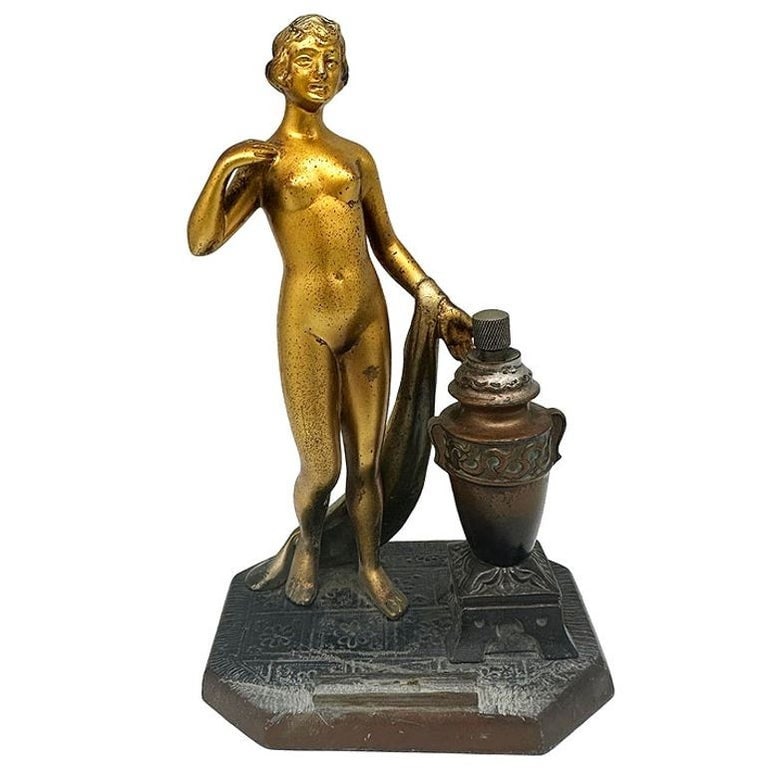Art Deco Spelter Metal Nude Flapper Goddess Desktop Torch Tip Table Lighter: Nude Greek Goddess spelter metal torch tip table lighter featuring a nude flapper gilded in bronze. The urn next to the goddess contains the oil and striker with the holder for the flint in the fort.M