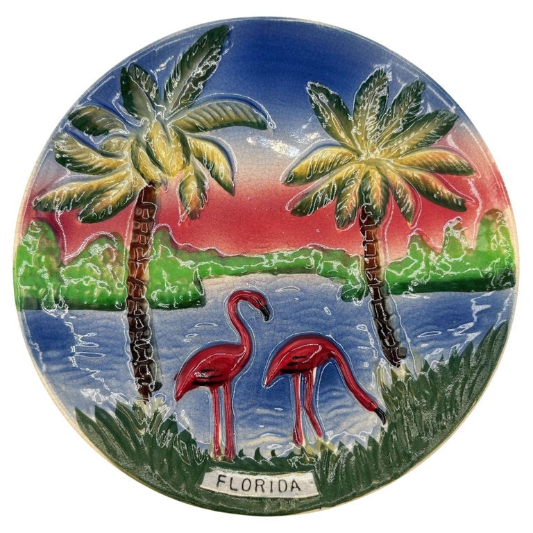 Mid-century Pottery Florida Sunset Flamingo Round Decrotive Wall Plate: Mid-century pink and green ceramic flamingo theme decorative wall plate. The wall plate features a beautifully detailed pair of pink flamingos on a sunset beach with the state "Florida" spelled out ac