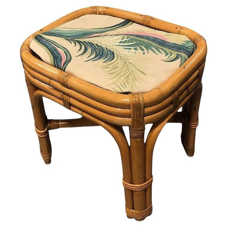 Restored Mid-century Rattan & Wicker Triple Arched Vanity Stool w/ Palm Fabric: This beautifully Paul Frankl-inspired rattan footstool/vanity Stool is adorned with palm leaf print barkcloth upholstery and rattan arched legs. The stool features a triple-strand rattan seat and trip