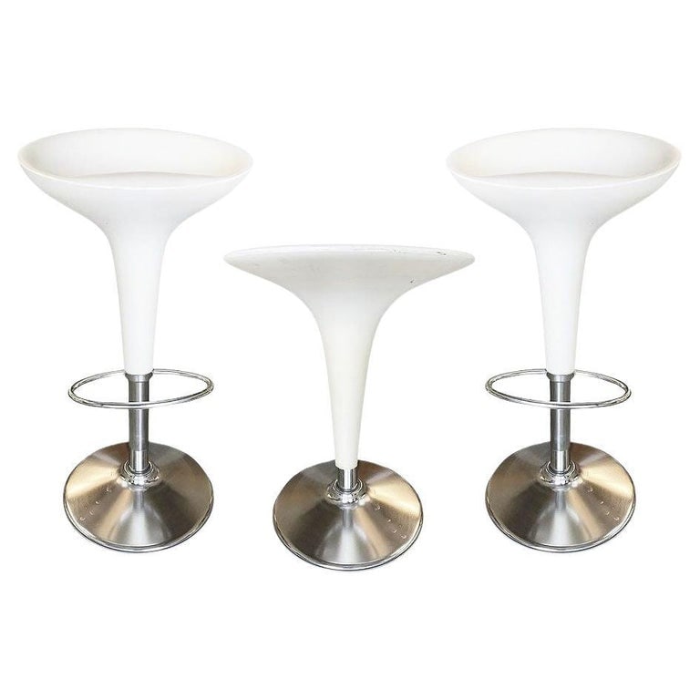 Philippe Starck Style White Modernist Stool and Table Set: Philippe Starck-style white modernist stool and table set featuring white plastic tops and chromed steel bases. The set includes 2 stools and one low-boy table.MeasurementsStools: 17.5" Diameter x 33"