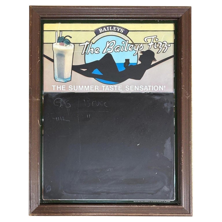 The Bailey's Fizz Female Silhouette in Hammock Chalkboard Bar Sign: The original 1980s Bailey's Fizz chalkboard bar sign features a silhouette of a nude woman lounging in a hammock with a sun setting behind her. Below is a small Chalkboard for specials of the day and