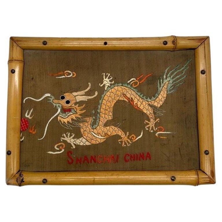 Post War Embroided Silk Art Imperial Chinese Dragon in Bamboo Frame: Post War II Chinese silk embroidery of a five-clawed imperial dragon in rendered orange thread against a green background. The words "Shanghai China" are embroidered below the dragon in its original b