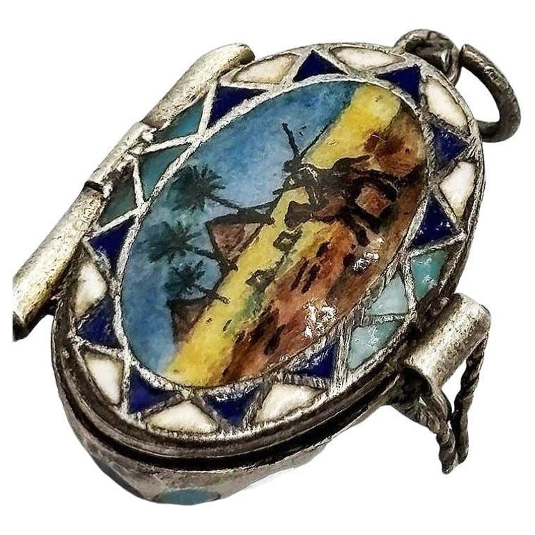 Egyptian Revival Sterling Silver Painted Enamel Locket w/ Gilded Gold Nude Mummy: The Egyptian Revival era of jewelry occurred during the Art Deco period when Tutankhamun's Tomb was discovered. The front is finished in fine hand-painted enamel detailing, depicting a man on a camel
