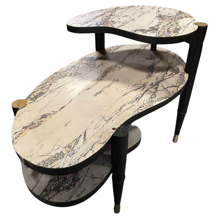 Mid-Century Modern Biomorphic Side Table with Formica Top: Original Googie-era biomorphic three-tier side lamp table, featuring a marbleized white Formica top and tapered ebonized legs with brass details along the foot and top. The table features a magazine