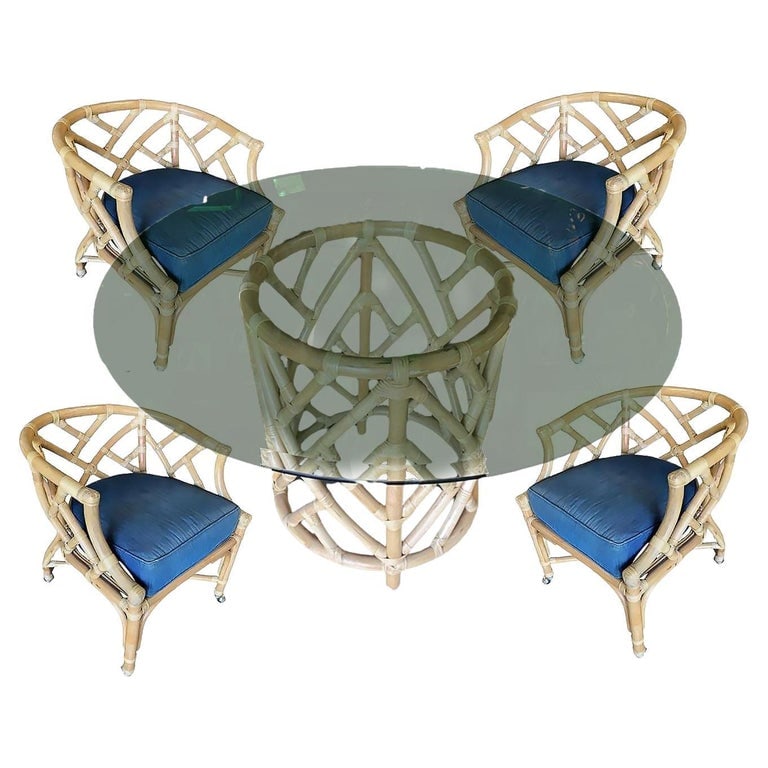 Round Pedestal Table and Geometric Bucket Armchair Rattan Dining Set: Rattan dining set with 4 Bucket style dining armchairs each with a Geometric seat back and blue cotton seat and a round rattan pedestal dining table with a 48" glass top. Each rattan chair features a