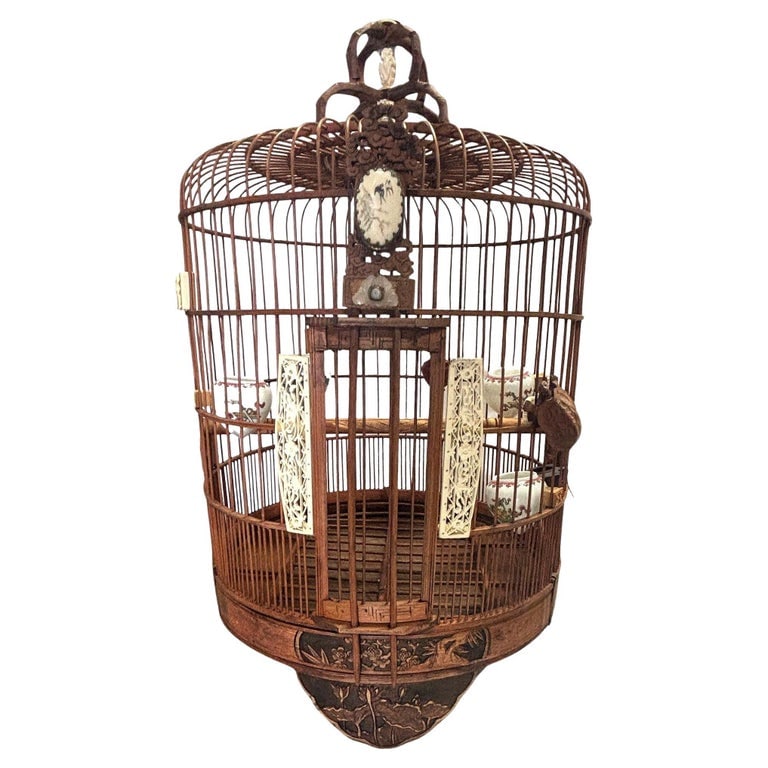 Antique Chinese Reed Rattan Birdcage Porcelain Bowls, Jade, with Pin Lock: This antique Chinese birdcage, crafted from red reed rattan, features porcelain feeder bowls. Adorned with jade and mother-of-pearl accents, it showcases exquisite craftsmanship. A pin lock secures th