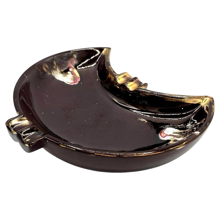 Mid Century Ceramic Crescent Shaped Glazed Ashtray Dish: Mid-century brown crescent-shaped ashtray with gold and multicolored accents. The rich brown glaze enhances its sculptural form, adding warmth and sophistication to its aesthetic. Thoughtfully crafted