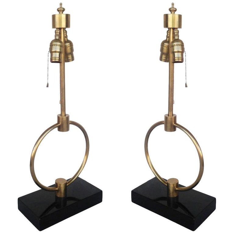 Mid-century Gilbert Rohde Style Brass Ring Table Lamp, Pair: Gilbert Rodhe style brass ring table lamp pair featuring a center brass ring fixed to a lacquered wood base. Each lamp has an elegant yet simple Mid-century design that fits easily into any setting. T