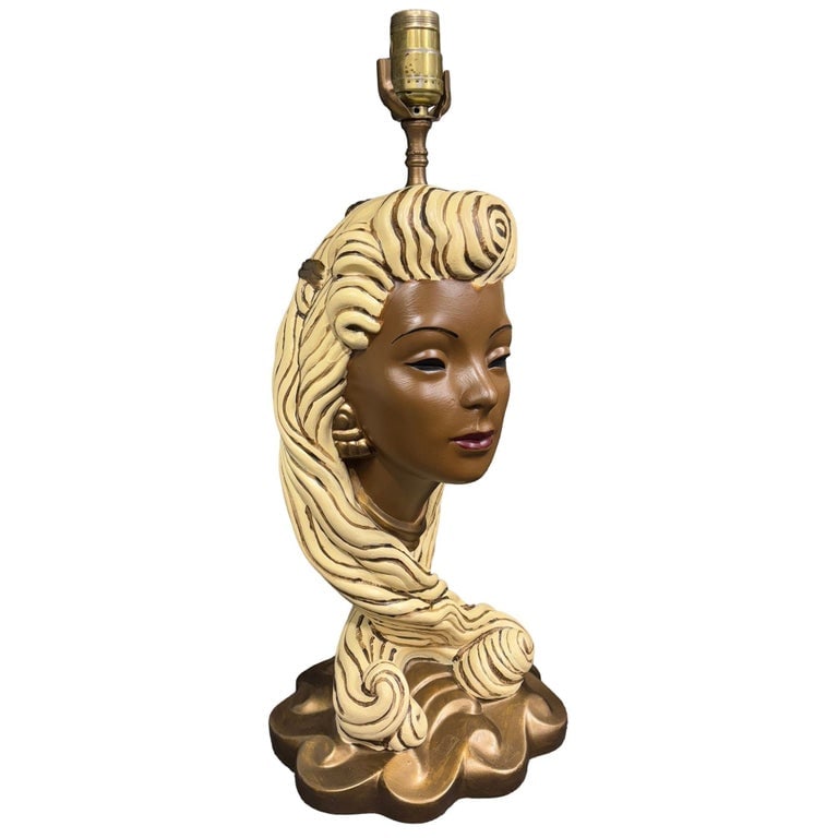 Mid-Century Female Bust Chalkware Lamp: This mid-century chalkware lamp showcases a detailed sculptural bust of a young Polynesian woman elegantly styled with flowing blonde hair and accented by gold accessories. A true vintage treasure, th