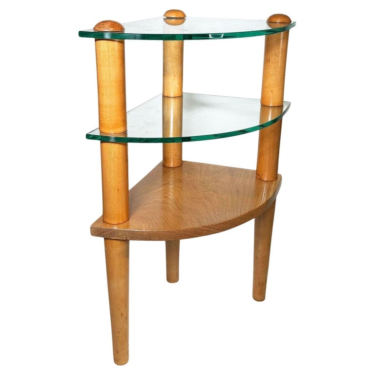 MCM Floating Glass & Walnut 25" Tall Corner Table Attributed to Gilbert Rohde: Elegant mid-century modern corner table attributed to Gilbert Rohde featuring a double-tiered glass top supported by sculptural, tapered walnut wood legs. It features thick, green-edged glass shelves 