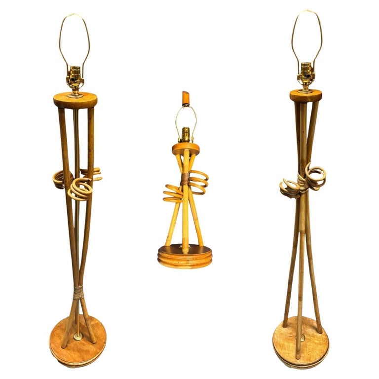 Restored Mid-century "Hourglass" Rattan Floor/Table Lamps Set of 3: These beautifully restored Paul Frankl-inspired Rattan lamps feature a pair of Floor Lamps and with Matching Tabletop Lamp. Each lamp features an elegant hourglass silhouette with bent rattan poles fi
