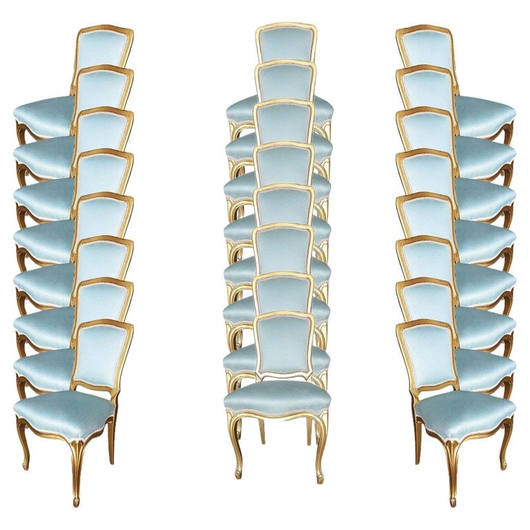 1950 Louis XVI-Style Hollywood Regency Gold Giltwood Dining Chairs, Set of 24: This set of 24 elegant French-inspired side dining chairs features a masterfully hand-carved gilt-wood frame with a lustrous gold leaf finish. Featuring a cabriole leg design with delicate scroll feet