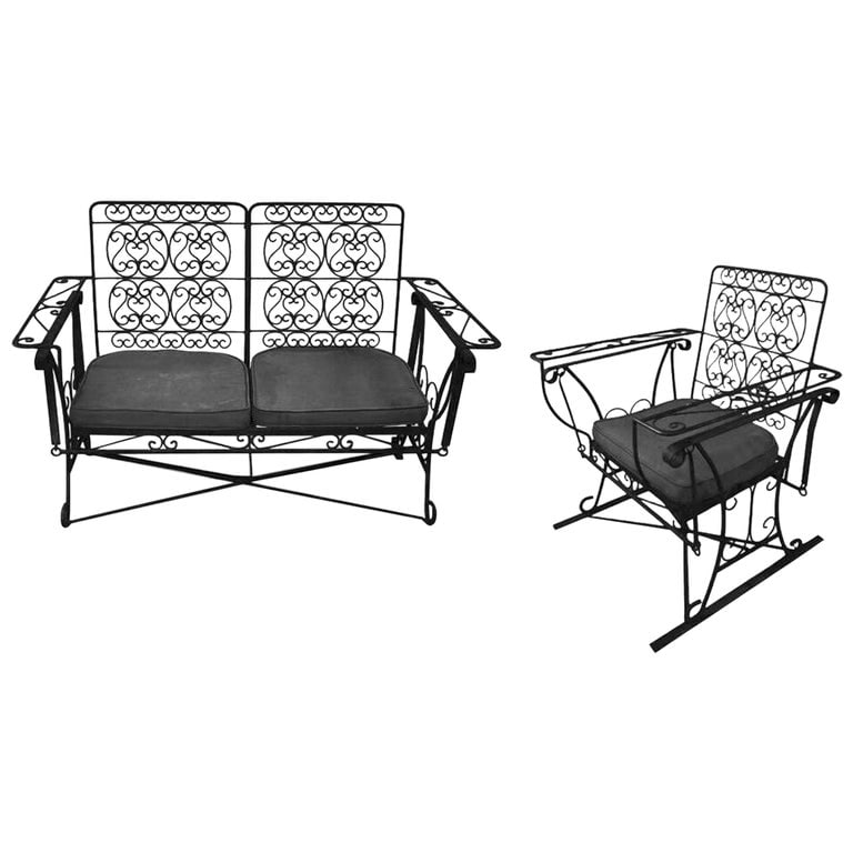 Black Scrolling Wrought Iron Glider Rocking Settee & Chair Patio Outdoor Set: A set of black 1950s Mid-Century Woodard style wrought iron wire patio/outdoor seating featuring a Glider lounge chair and Settee. Each features a scrolling seat back and armrests resting on a hinged 