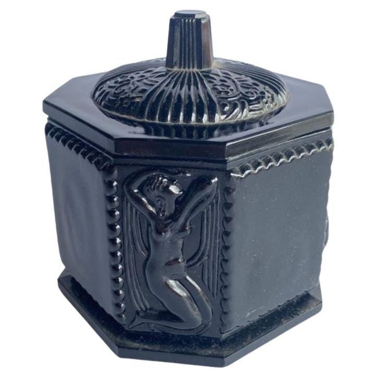 Art Deco Black Amethyst Tiara Glass Vanity Jar with Nude Woman: This antique 1920's classical black amethyst hexagon shaped Tiara Glass vanity jar presents a captivating blend of elegance and antiquity. Crafted with meticulous detail, the jar features a Greecian n