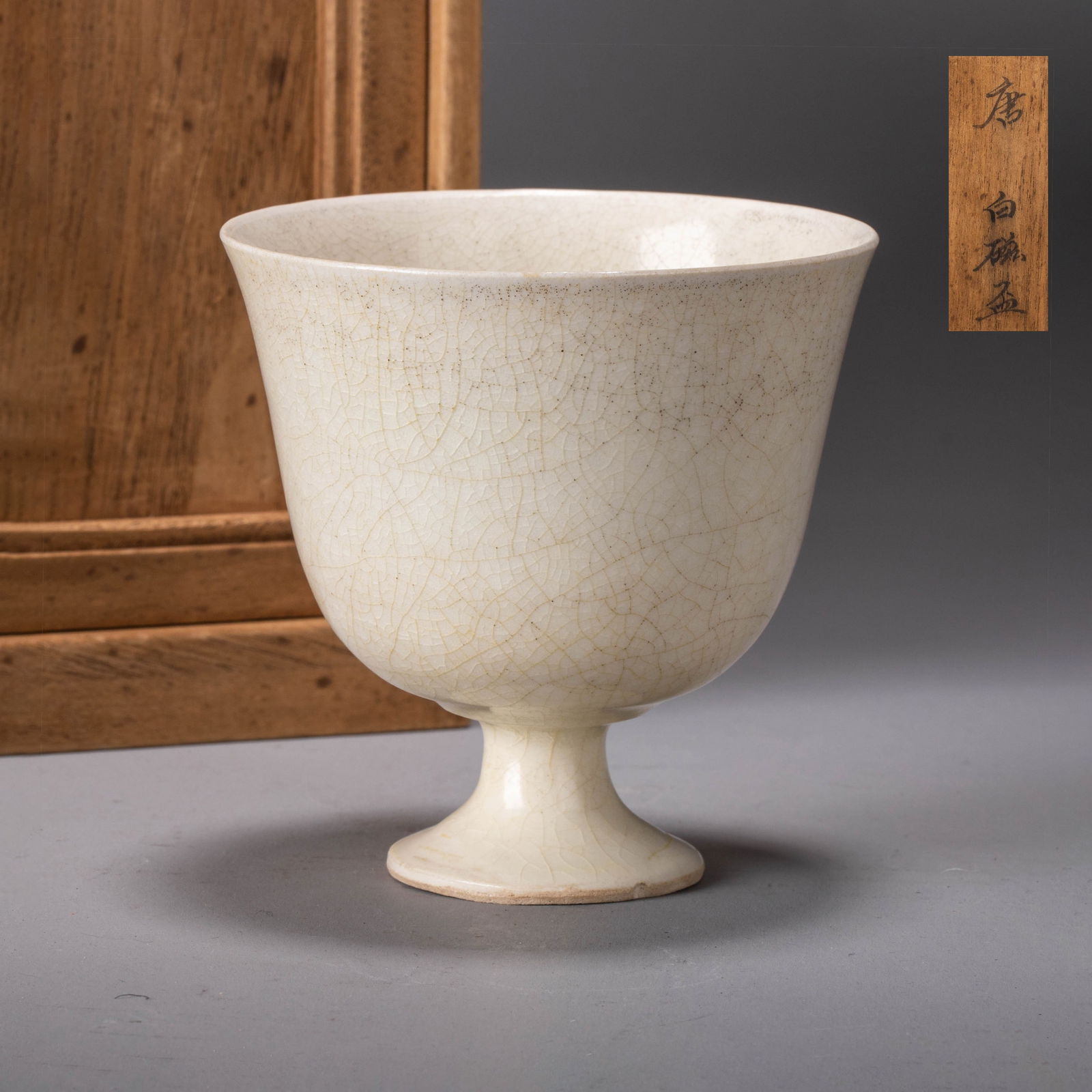 Sui Dynasty white porcelain cup: Sui Dynasty white porcelain cupElegant flared rim and high-waisted foot; smooth bluish-white glaze with fine ice-crack patterns; undecorated, showcasing refined form and transitional Sui celadon-to-wh
