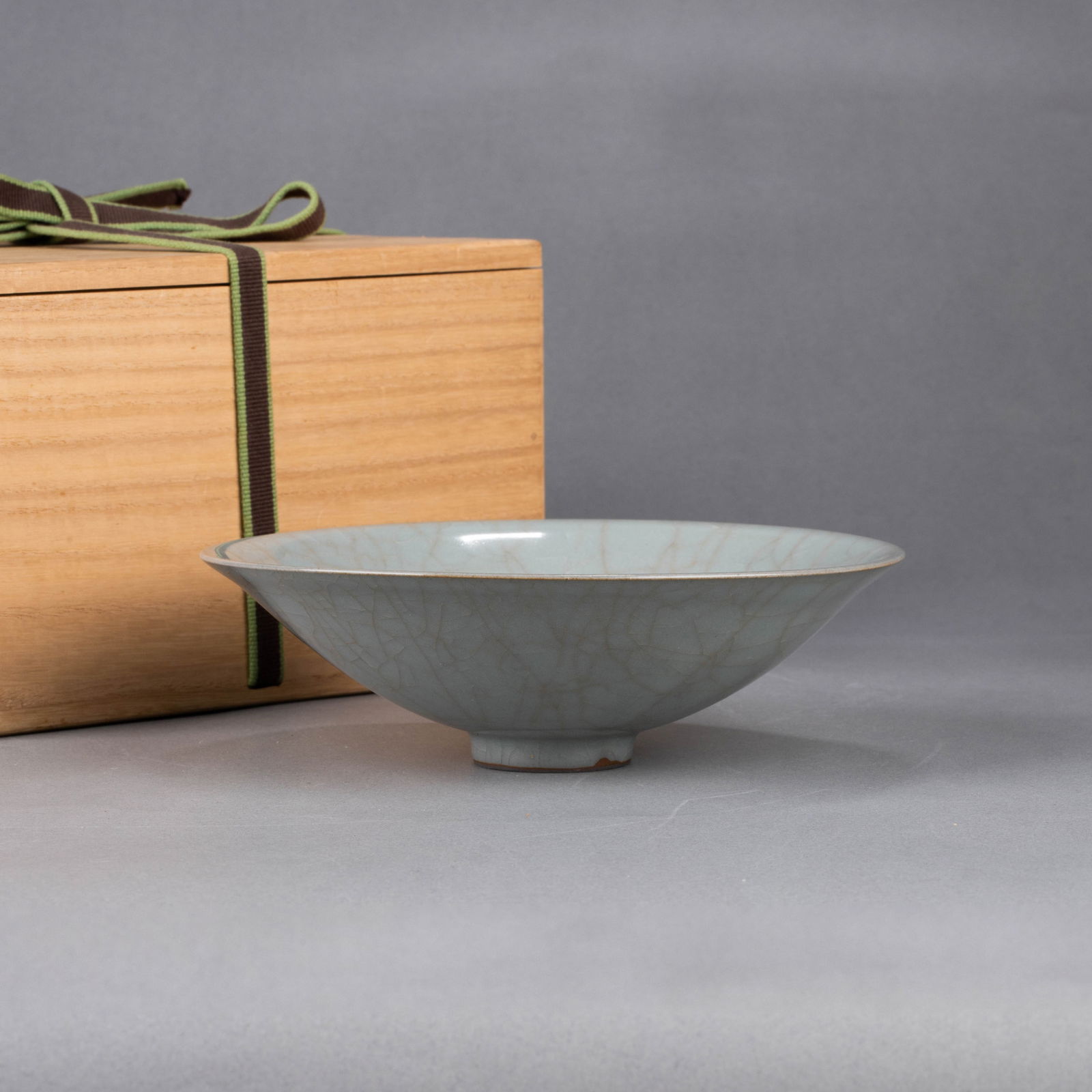 Southern Song Dynasty Longquan Official Kiln ‘Douli’ cup: Southern Song Dynasty Longquan Official Kiln “douli”-shaped cup – Flared rim, shallow body with ring foot; lustrous pale-blue glaze with fine crackle and subtle purplish rim; dark iron-rich