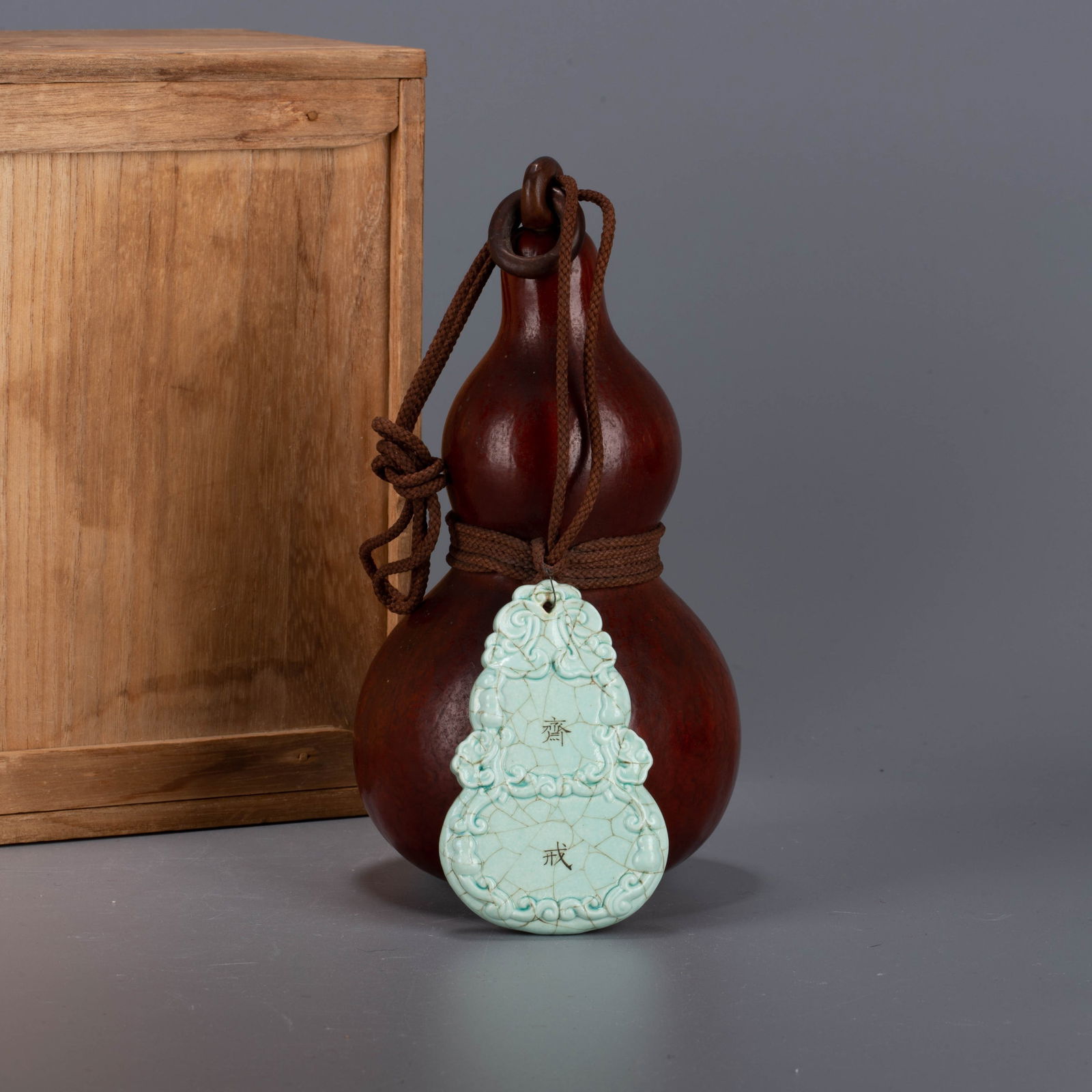 Qing Dynasty Turquoise-Green Ground Famille Rose Abstinence Tablet: Qing Dynasty Turquoise-Green Ground Famille Rose Abstinence Tablet - This piece is crafted from a natural gourd, distinguished by its deep brown color and smooth, lustrous patina. A cord is tied aroun