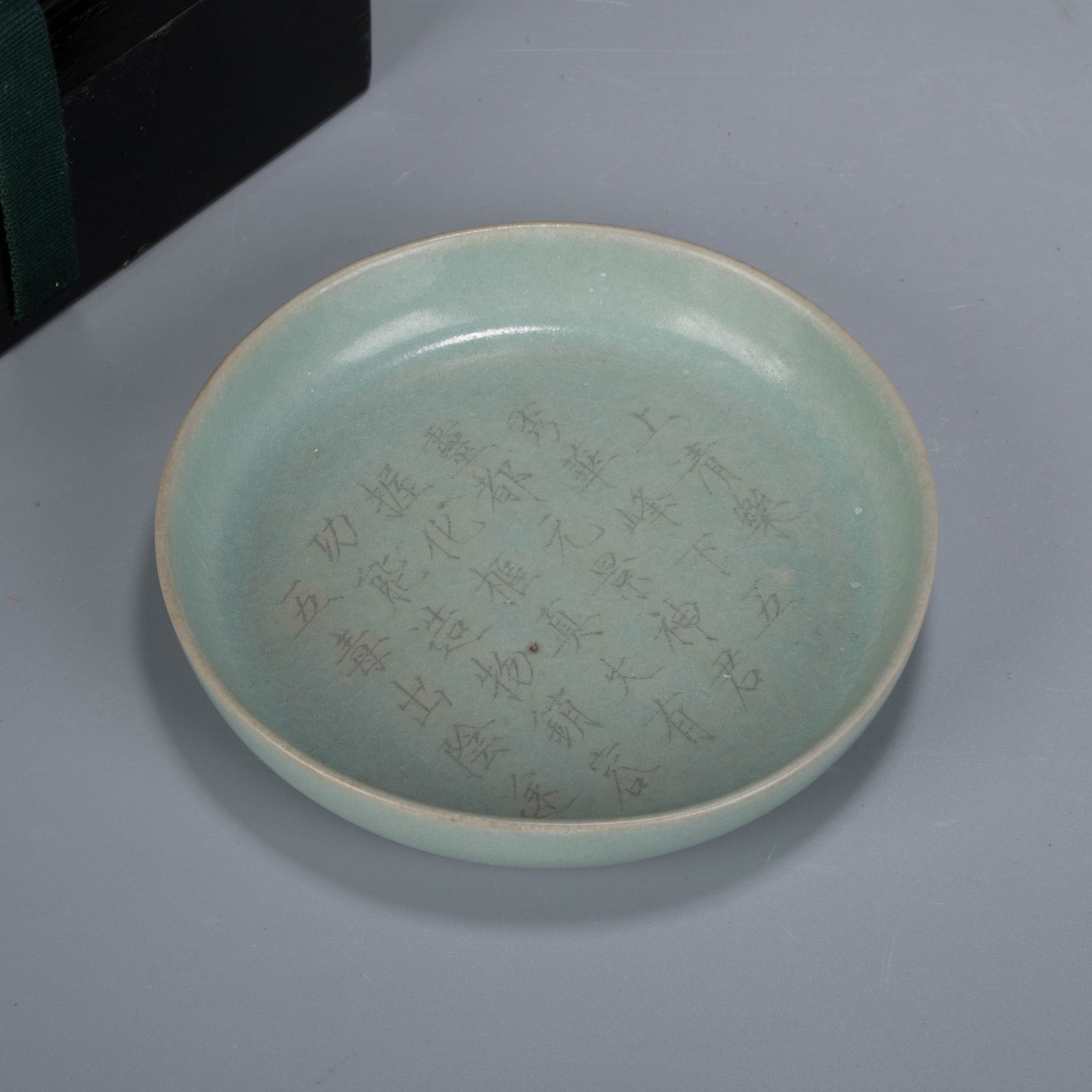 Song Dynasty Ru kiln brush washer Yuti "Please enjoy the music - the sixth Zhao Ji": A dish-shaped form with a flared mouth, shallow body, and flat base. The entire surface is covered in a celadon glaze of soft and even tone, with a faint yellowish tint along the rim. The interior is