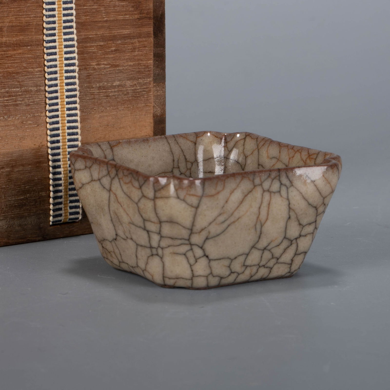 Song Dynasty Ge Kiln Japanese Jiao Cup: This wajiao cup is a classic scholar's utensil from the ge kiln of the Song Dynasty. it is square in shape, with introverted arcs at the four corners of the mouth, a deep belly with a sloping wall, an