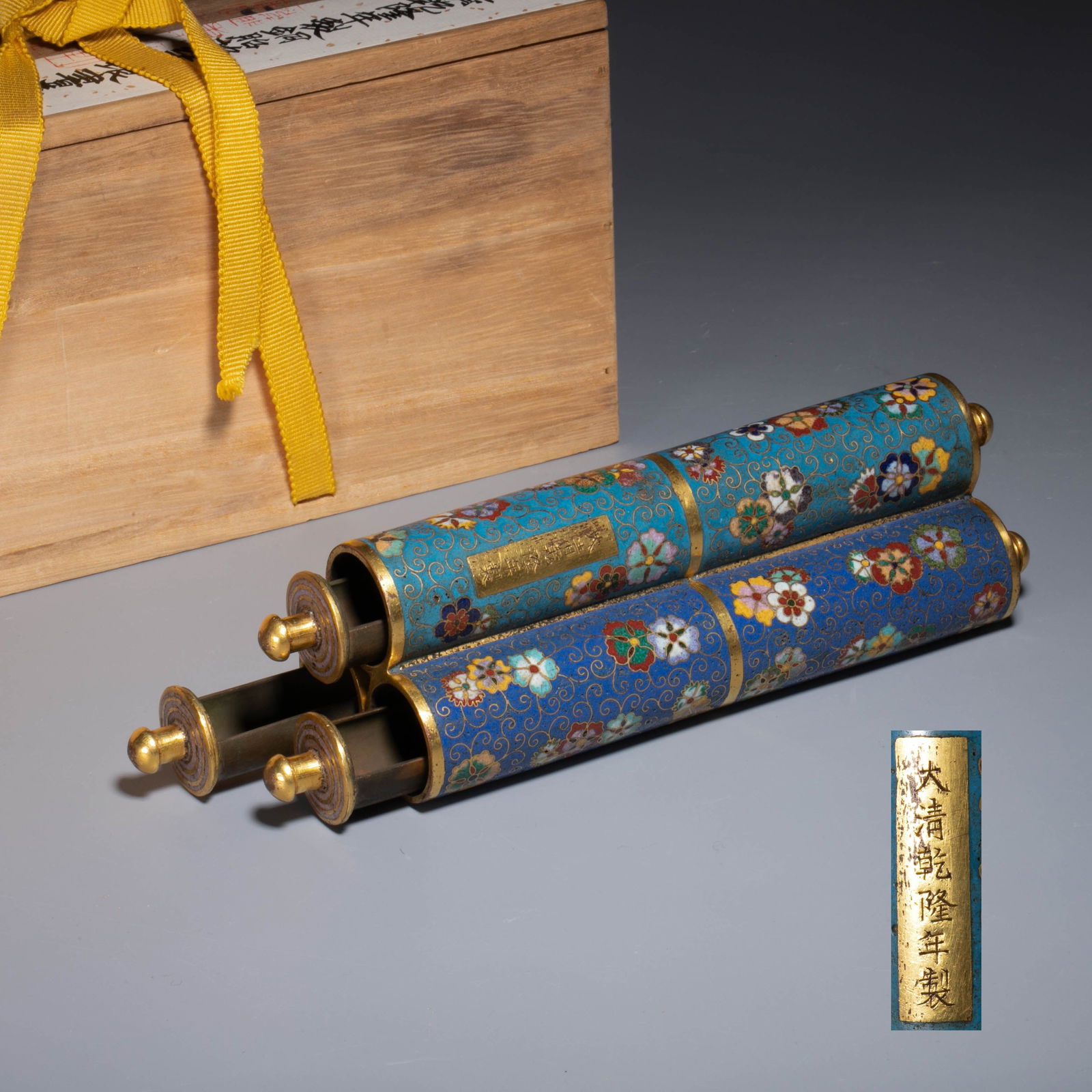 Copper Cloisonné Enamel Scroll-Form Covered Box, Marked “Made in the Qianlong Period of the Great: This covered box is made of copper and is shaped like a scroll and is rectangular. the whole body is made of sky blue enamel, and is decorated with gold threads and lotus branches. the branches and le