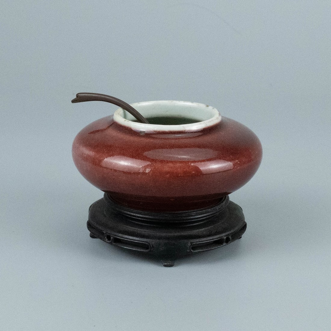 Qing Dynasty red glaze water bowl: The water basin has a narrow mouth, a flat and round belly, and a full and thick shape. When placed on a wooden base, it looks more stable and elegant. The whole body is covered with red glaze, the gl