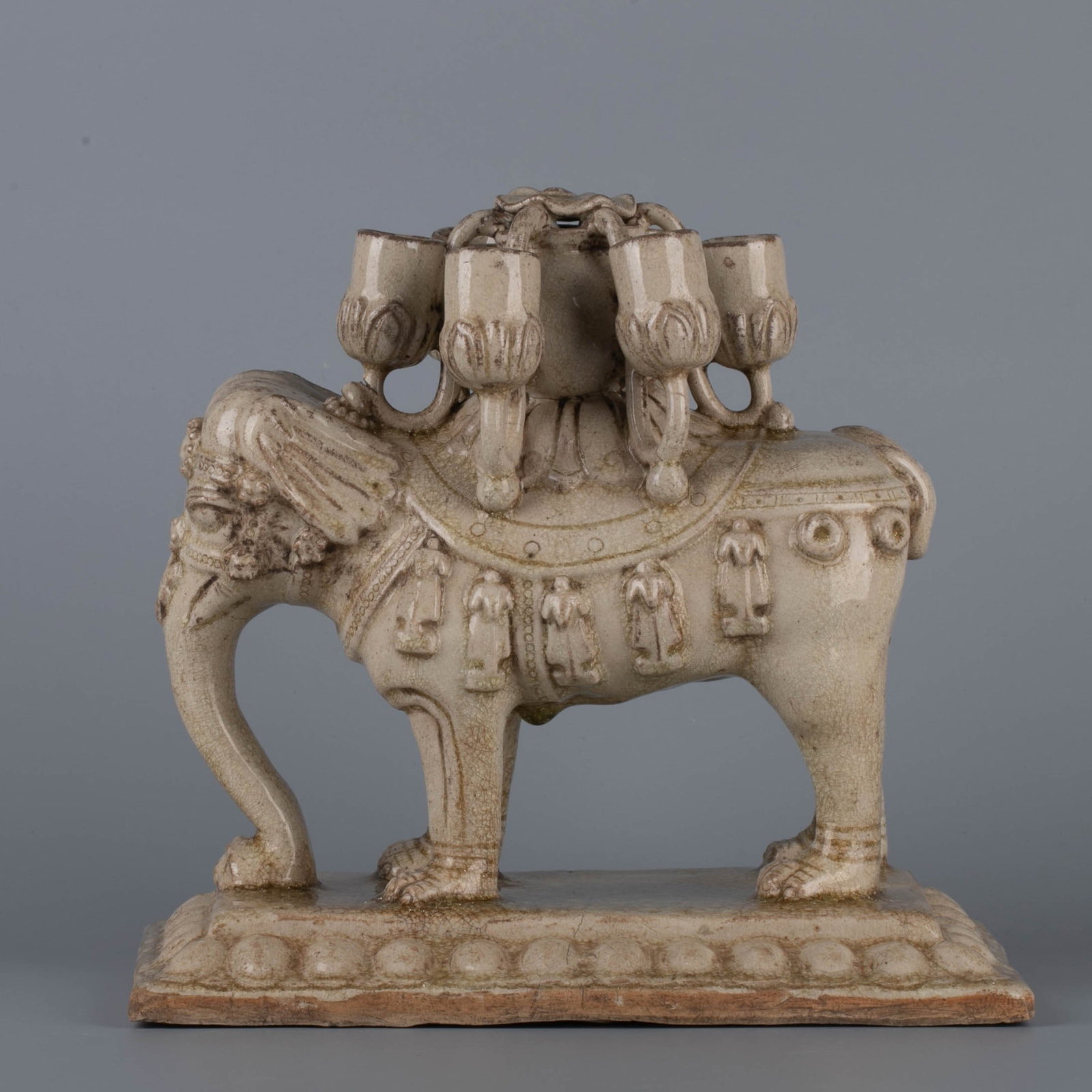 Sui white glazed pictographic candlestick: This white-glazed pictographic candlestick from the Sui Dynasty is shaped like a standing elephant with a round and solid body. Its four legs are firmly planted on a rectangular base. The elephant's
