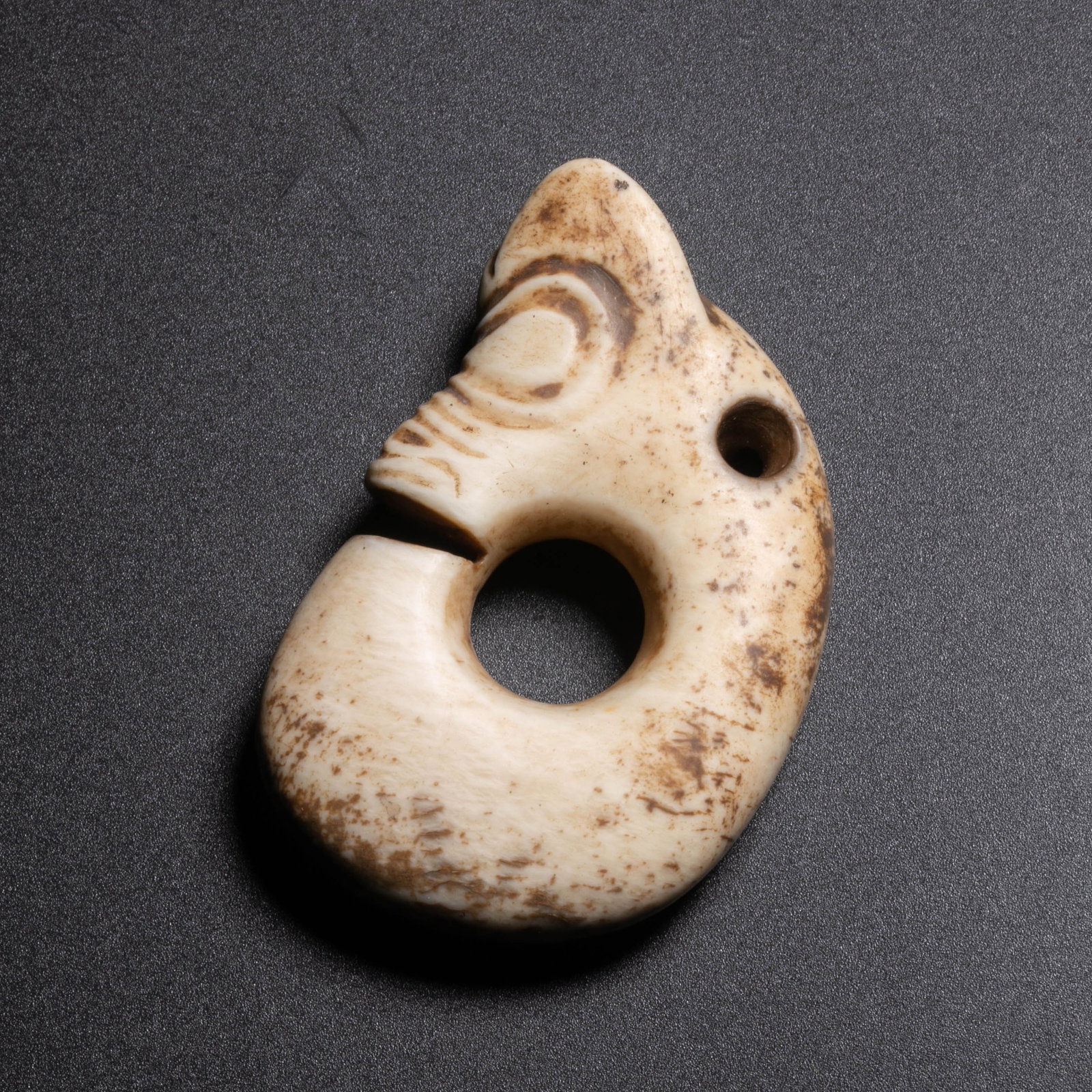 Hongshan Culture Chicken Bone White Jade Pig Dragon: This jade pig dragon from the Hongshan Culture is curled in a "C" shape, connected end to end, and the overall lines are round and full.The body of the vessel is carved from Xiuyan jade. Due to being