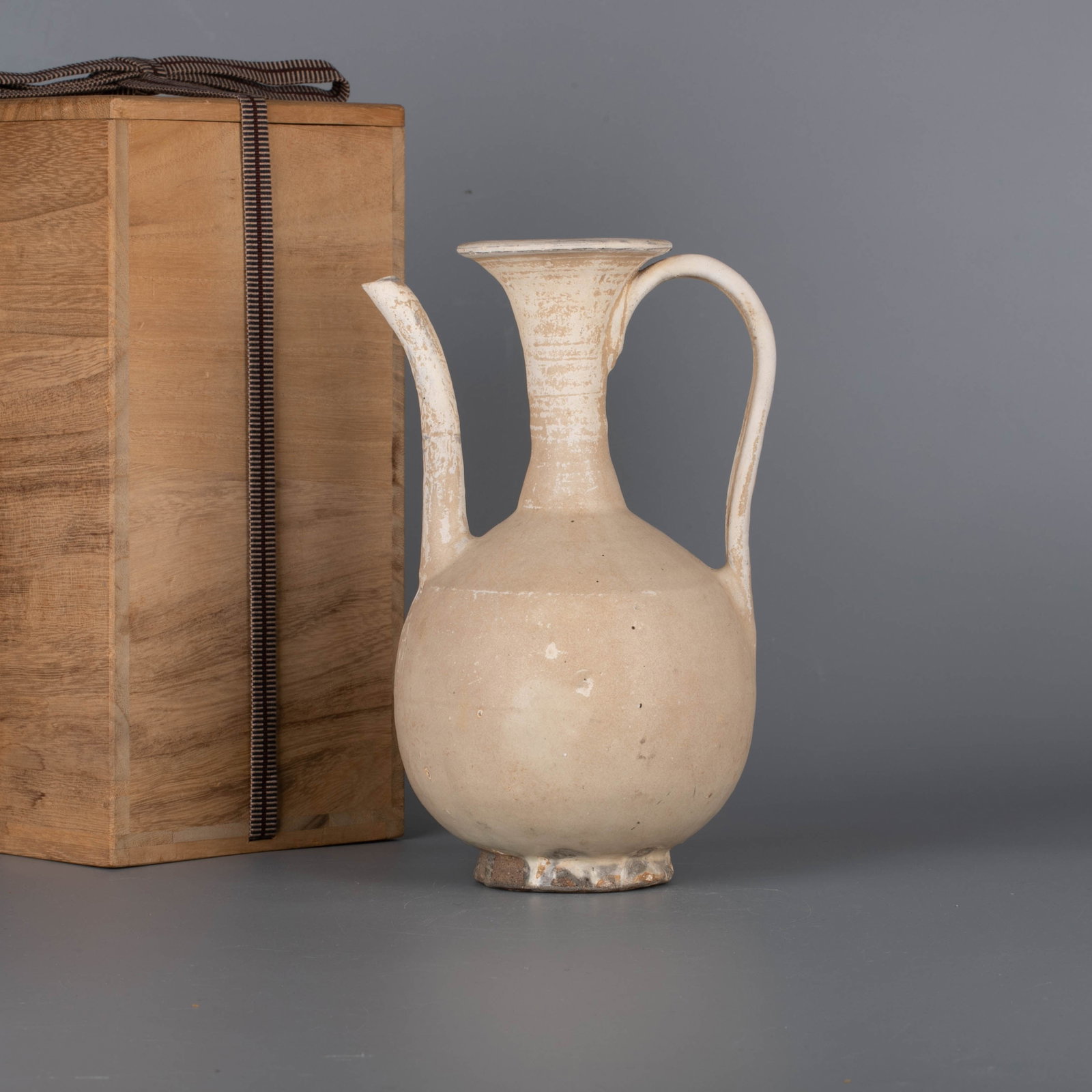 Song Dynasty white glaze teapot: This is a white-glazed long-necked ewer with a style that points to the Song Dynasty.The pot has a curved mouth, a long straight neck, a round belly, and a ring foot underneath. One side is equipped w
